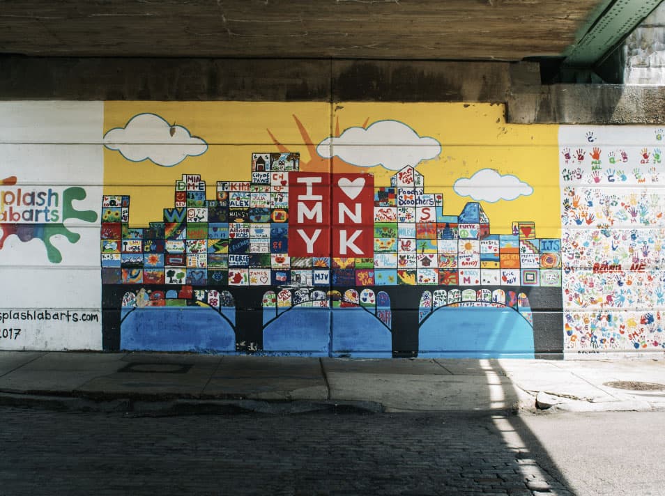 A colorful mural featuring the text "I ❤️ NY" surrounded by artistic representations and handprints.